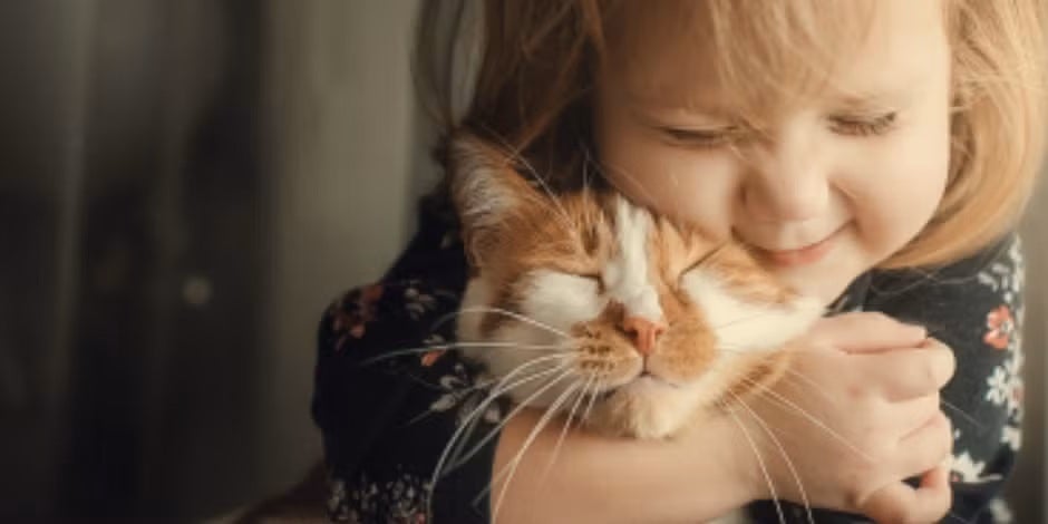 Escolher o nome certo para o seu gatinho deve ser uma decisão bem pensada. (Menina abraçando seu gatinho.)