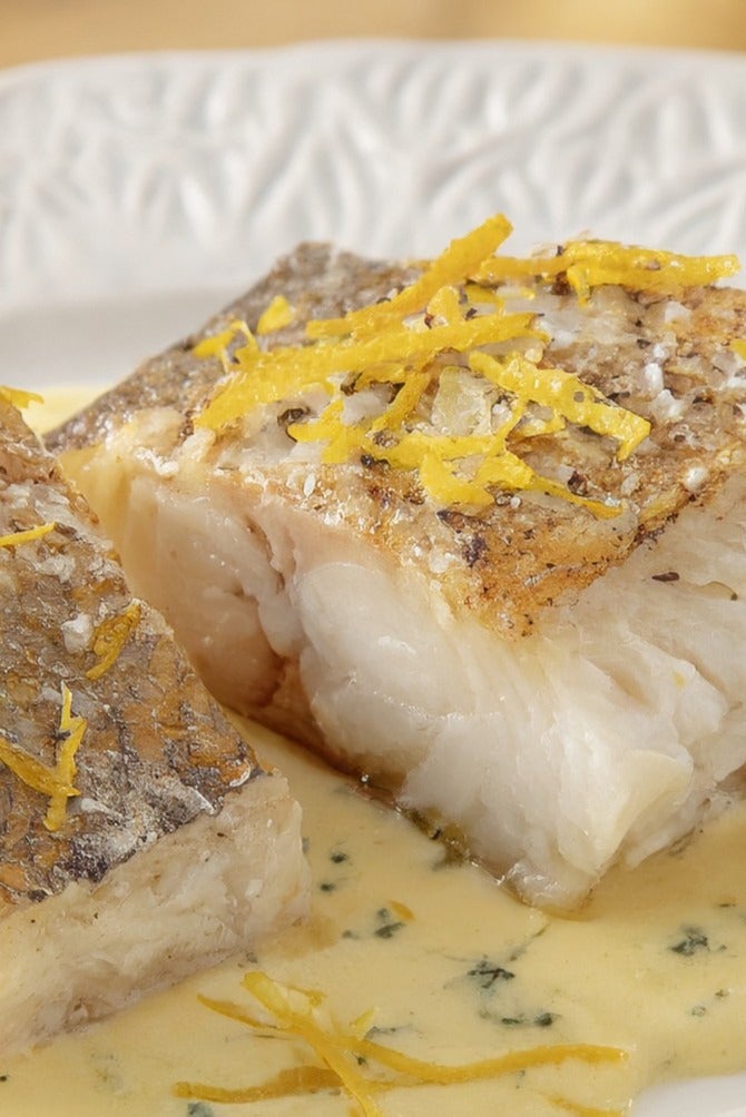 Bacalhau confitado com raspas cítricas e creme em um prato branco