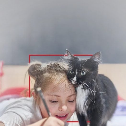 Menina com síndrome de Down desenhando ao lado de um gato preto e branco