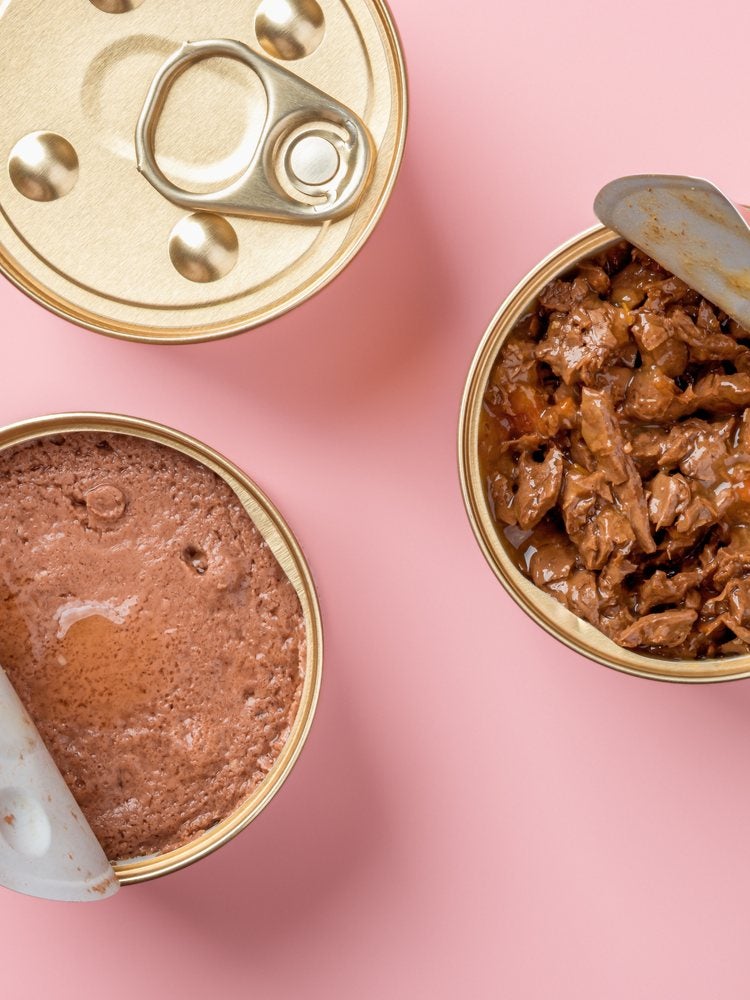 Latas de alimento úmido para pets abertas sobre fundo rosa