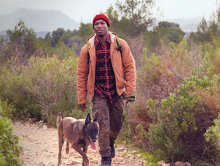 Homem caminhando com seu cachorro em uma trilha na natureza